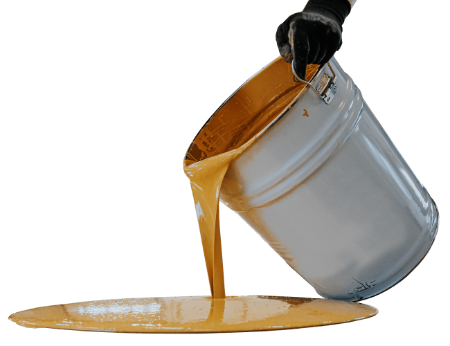 Golden paint pouring from a silver bucket onto a surface, creating a spill. A gloved hand holds the tilted bucket, showcasing the thick, flowing liquid.